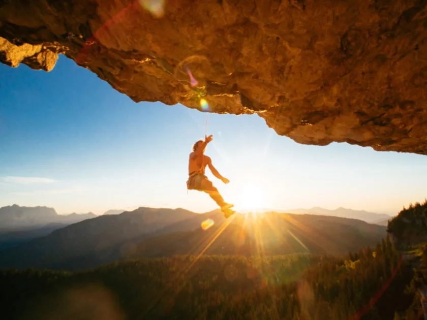 Mann hängt am Kletterseil an einem Felsen