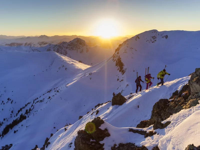 Drei Skitourengeher wandern auf einen schneebedeckten Gipfel