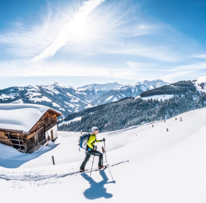 Ein Skitourengeher geht im Tiefschnee bei einer Hütte vorbei