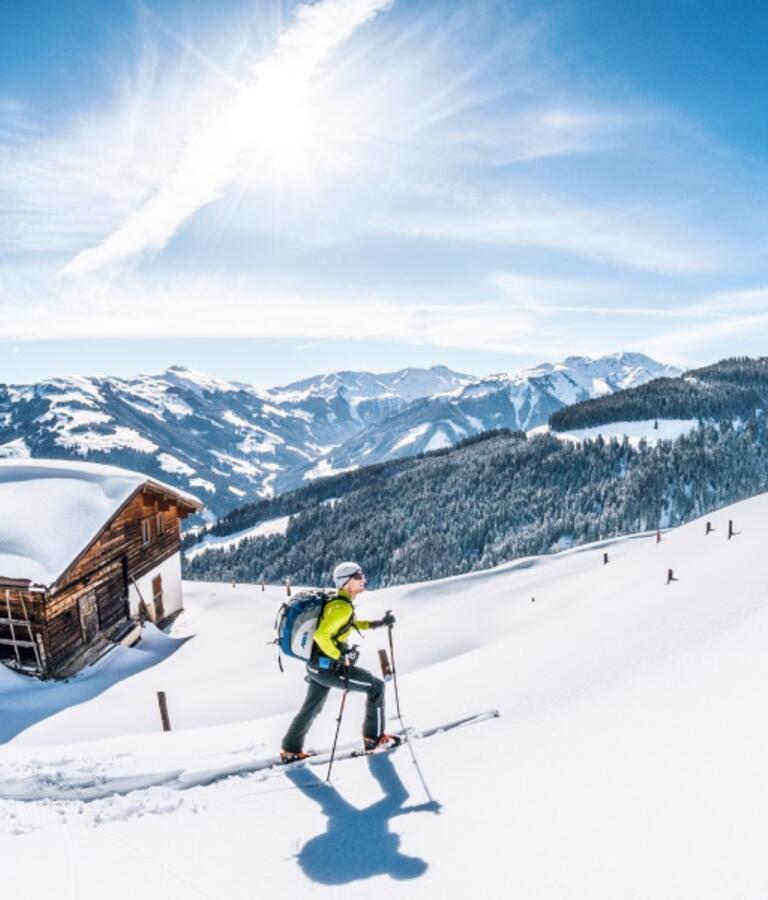 Ein Skitourengeher geht im Tiefschnee bei einer Hütte vorbei