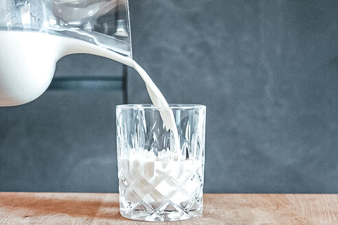 Milch, das von einer Karaffe in ein Glas geschüttet wird