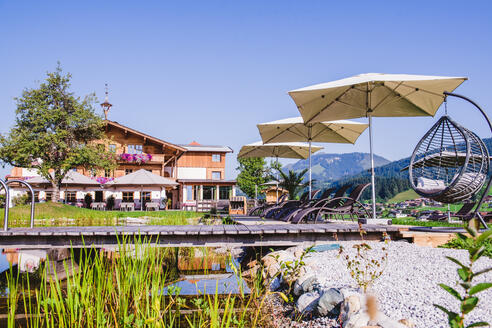 Außenansicht Hotel Sommer mit Schwimmteich im Vordergrund